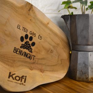 Una fusta gravada amb el texte El teu gos és benvingut penjada a la porta de la cafeteria Kofi